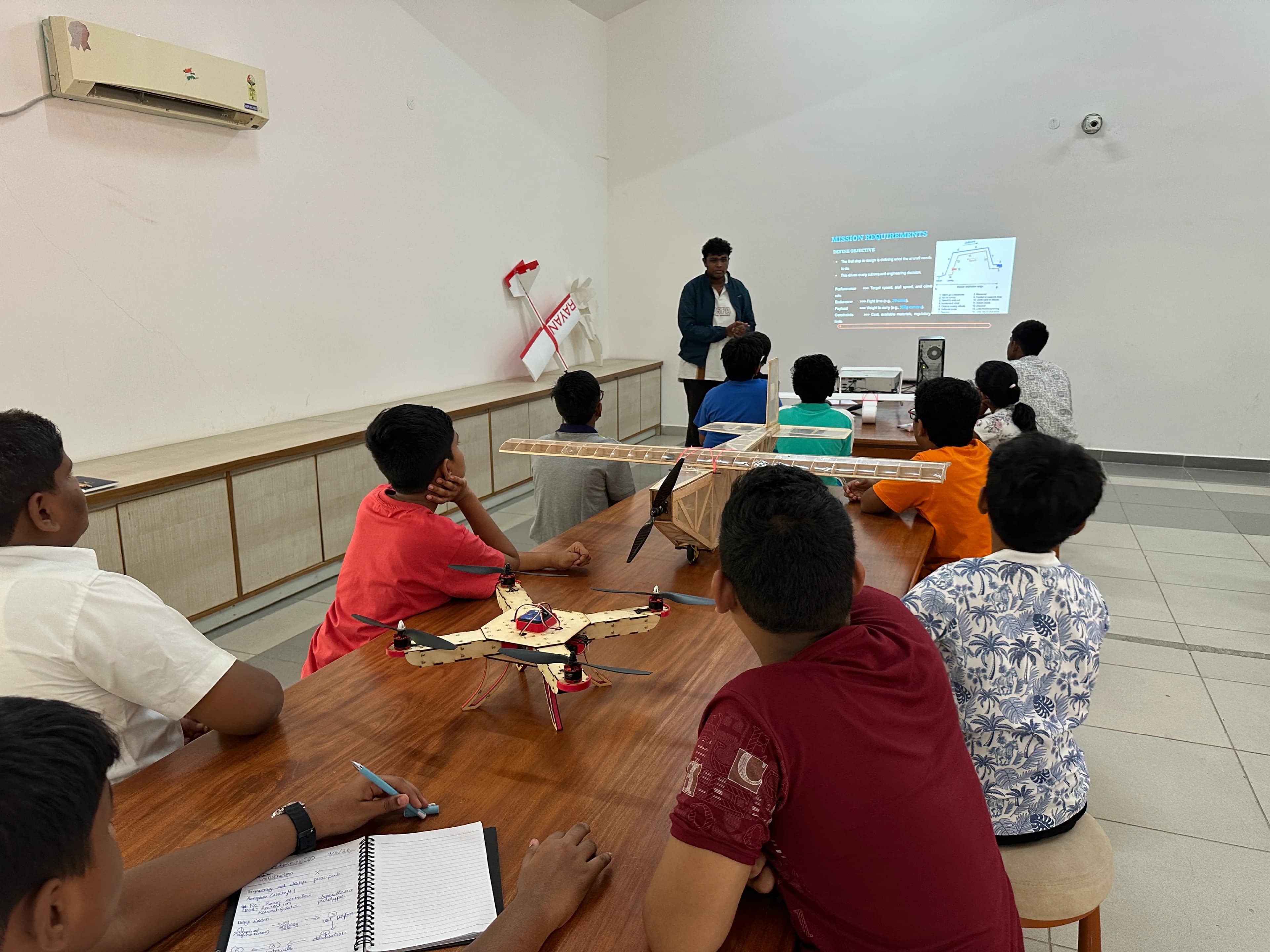 Classroom drone workshop with a laser-cut quadcopter and balsa-wood aircraft on the desks